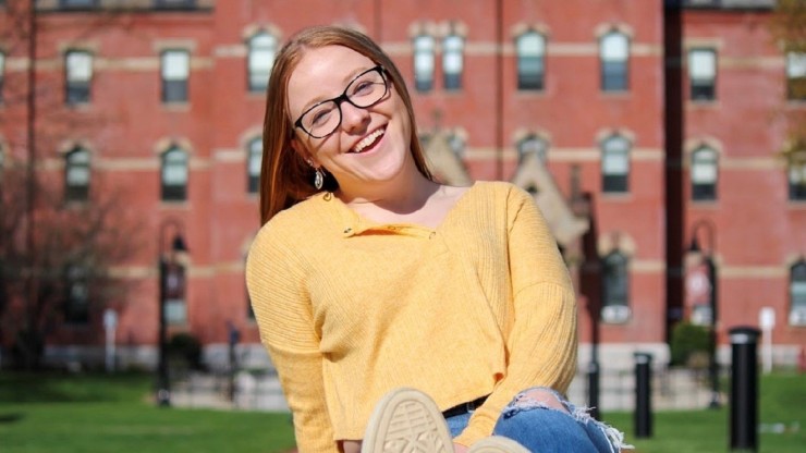 Dean Student sitting outside Dean Hall