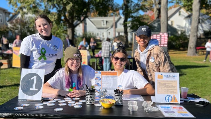 Four members of Project Green outside at a table during Fresh Check Day