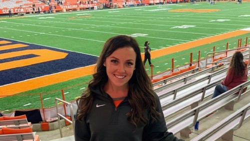 Student standing in the stands at an athletic field